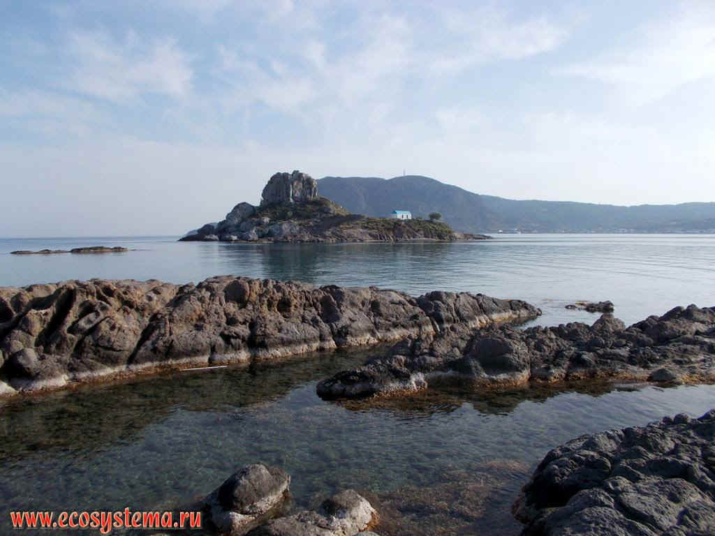 A small island of Kastri with the hurch and the abrasive shore of the Aegean Sea in the Bay of Kefalos on the South-West coast of the island of Kos